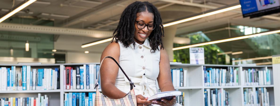 Student in library examining book.