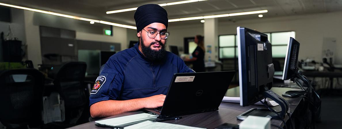 Bhavdeep in front of a laptop in a classroom.