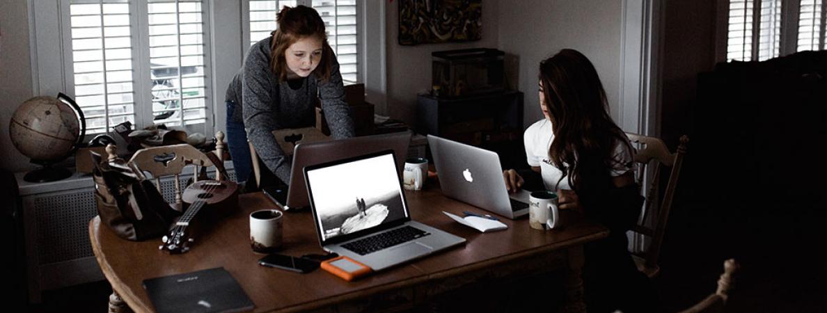 2 females working on laptops at a dining room table
