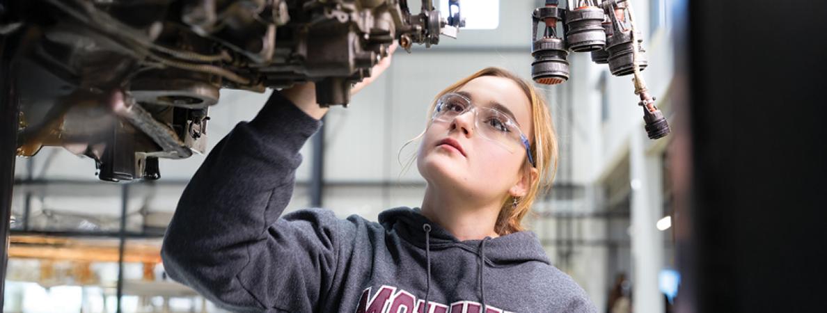 Elizabet examining an aircraft engine block.