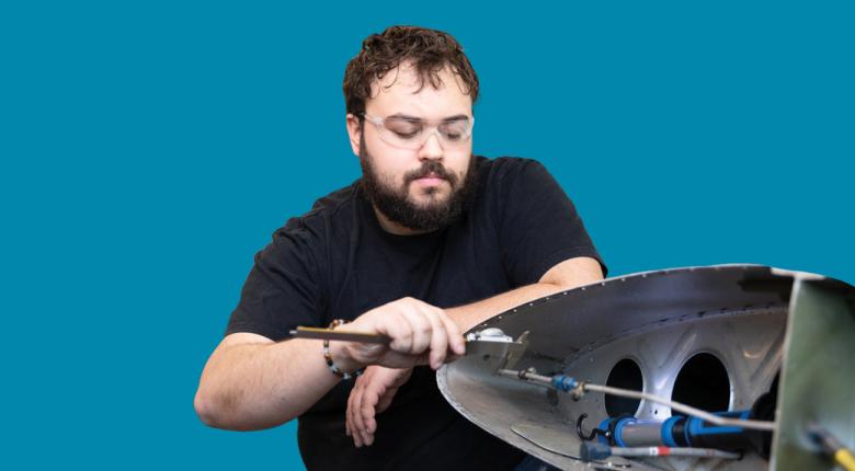 Student mechanic working on aircraft wing components.