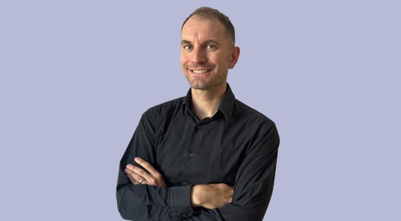 Man posing with arms crossed and smiling.