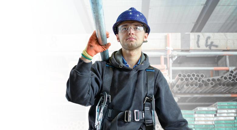 Student wearing a hard hat and goggles while carrying steel.