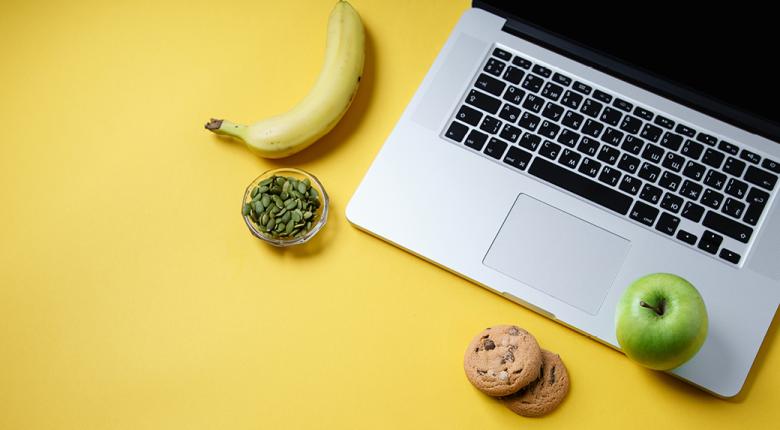 Banana, nuts, cookies and apple on a laptop.