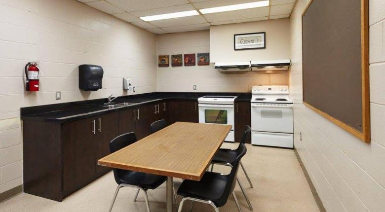 common kitchen on the first floor featuring a dining table for 4, black granite countertops with a sink, and 2 ovens.