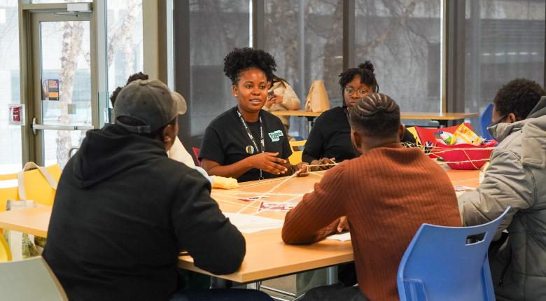 A group of 4 students sitting on a roundtable discussing. 