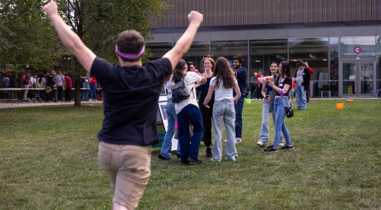 Student with hands up running towards his team members