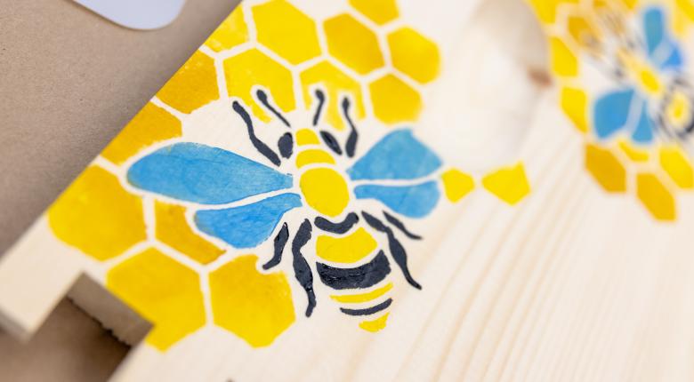 A bee and honey comb painted on a bee panel. 