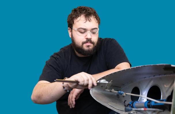 Student mechanic working on aircraft wing components.