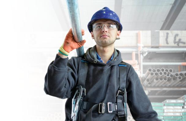 Student wearing a hard hat and goggles while carrying steel.