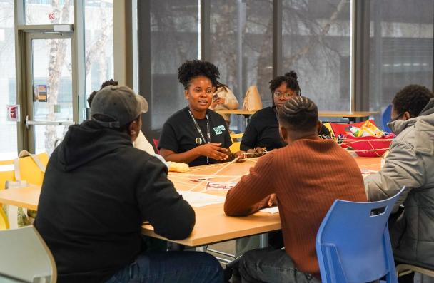 A group of 4 students sitting on a roundtable discussing. 
