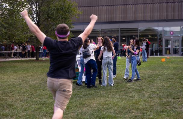 Student with hands up running towards his team members