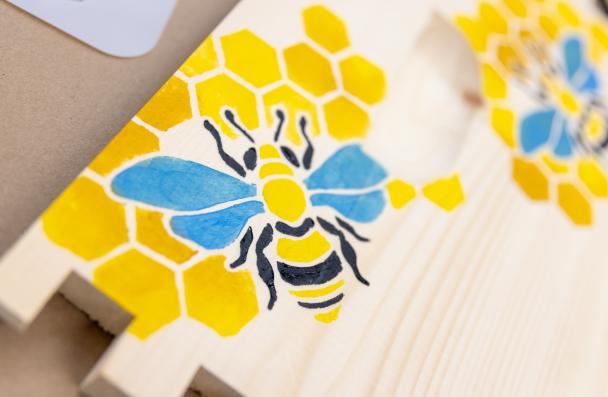 A bee and honey comb painted on a bee panel. 