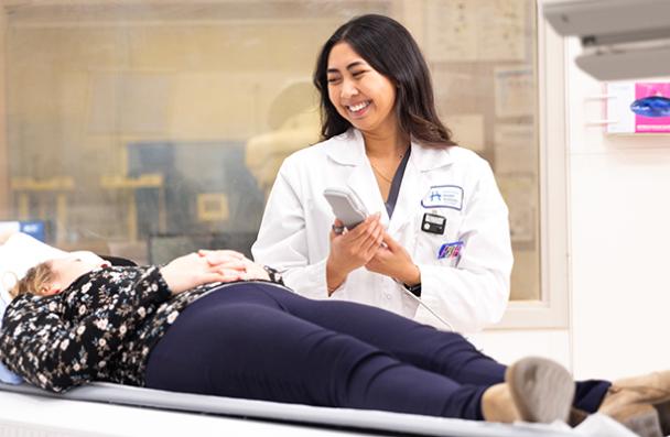 A tech talking with a patient on an MRI bed.