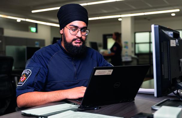 Bhavdeep in front of a laptop in a classroom.