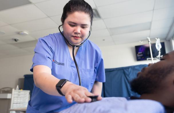 Uyen examines a patient with a stethoscope.