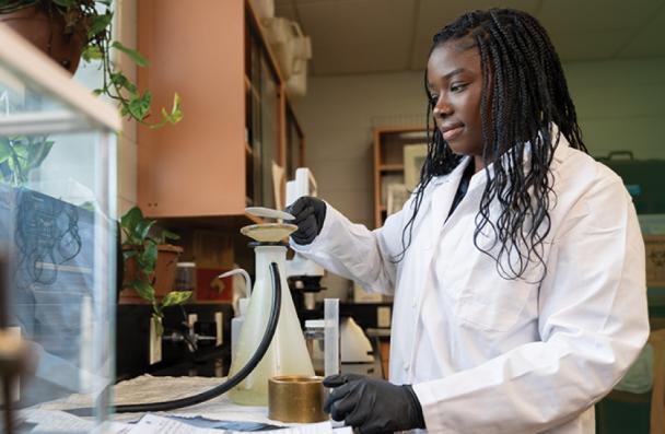 Tamiah in a lab coat with a beaker in a laboratory.