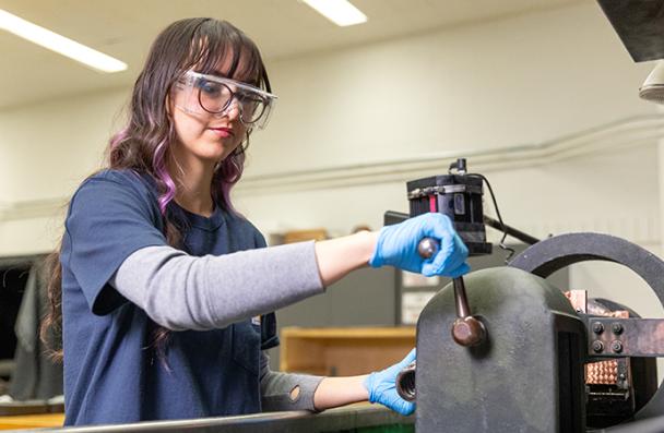Daniella wearing safety goggles while operating test machinery.