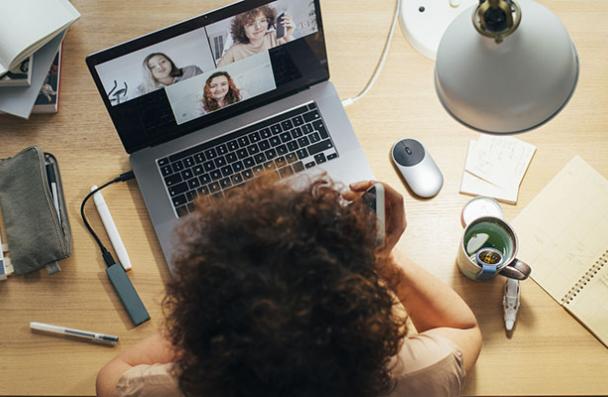 above shot of woman working at desk on laptop zoom call with 3 people