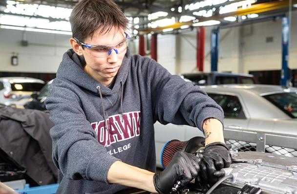 Keywayden working on a car engine in a Mohawk College automotive lab.
