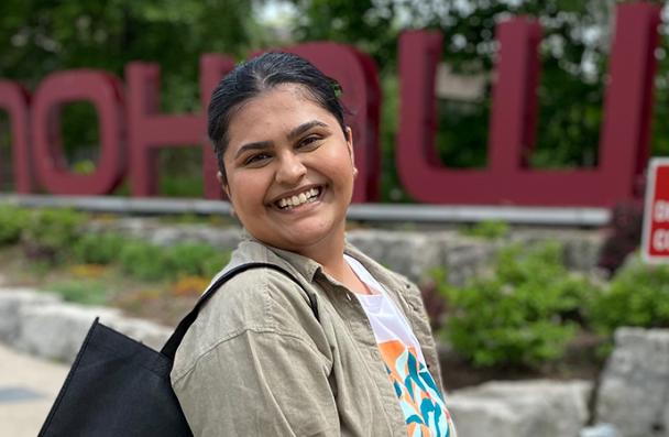 Gagan standing in front of the Mohawk sign smiling