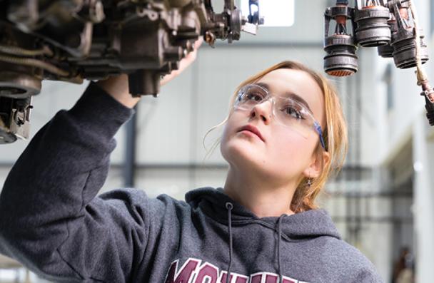 Elizabet examining an aircraft engine block.