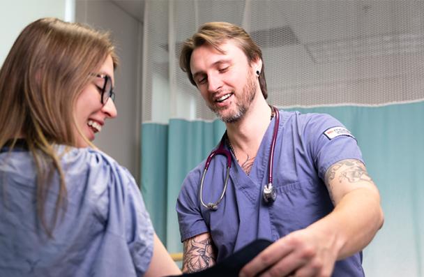 Two medical students demonstrating a pressure cuff.