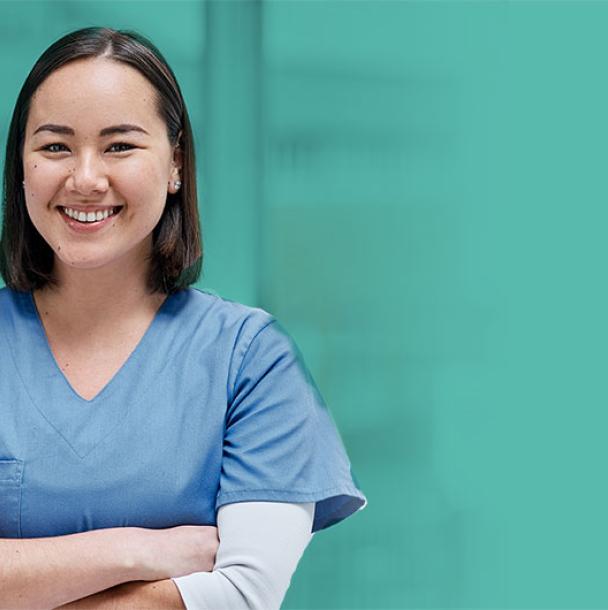 Nurse in scrubs smiling with her arms crossed