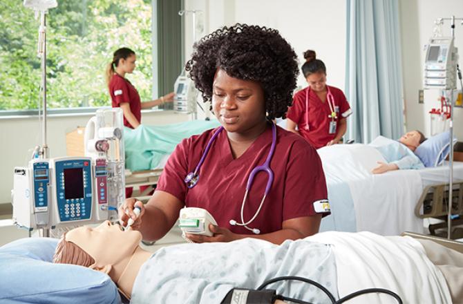 Healthcare student taking a manikin's temperature.