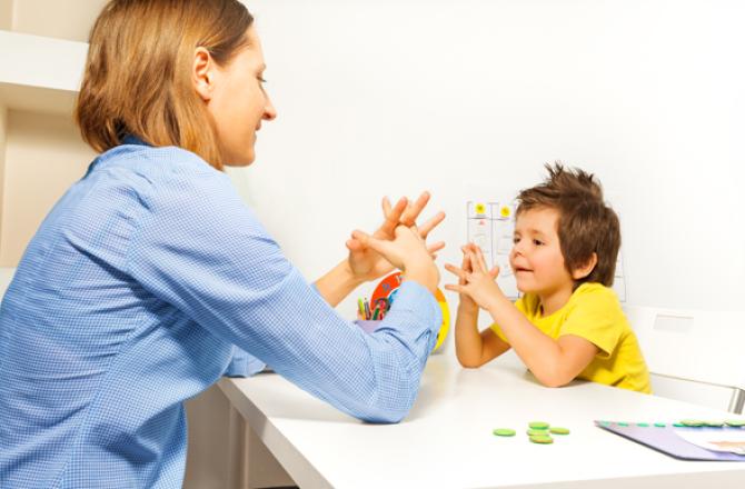 Student showing autistic child how to interlace their fingers.