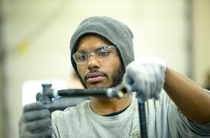 A man wearing safety glasses and gloves working on pipes.