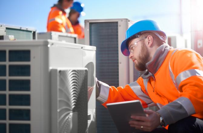 Utilities Systems Operator examining an industrial air conditioning unit.