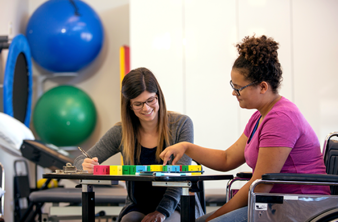 An occupational therapist works with a person in a wheelchair.