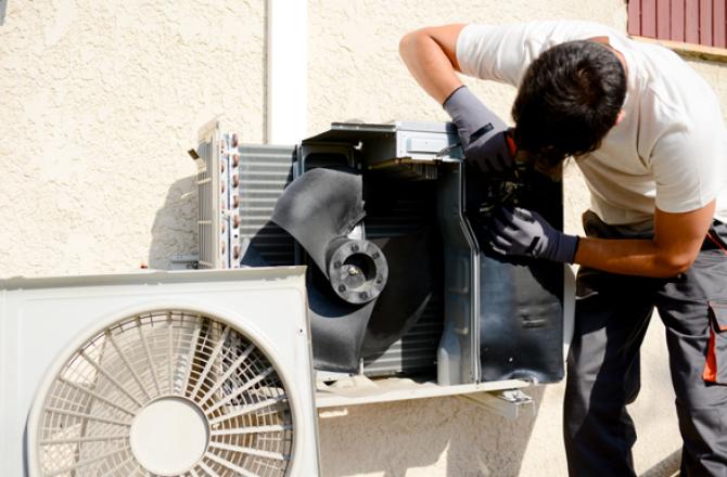 Refrigeration mechanic working on a residential air conditioning unit.