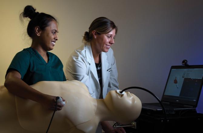 Mohawk College diagnostic cardiac sonography student and instructor examining a manikin attached to a laptop.