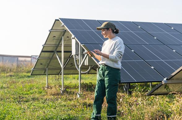 Young woman taking field notes in front of solar panels