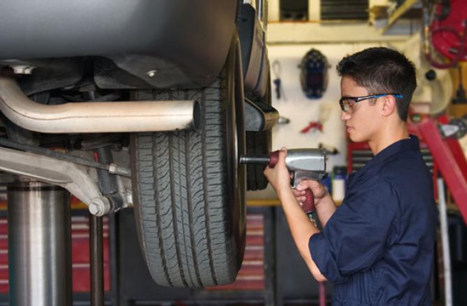 Mechanic removing lug nuts on a car wheel.