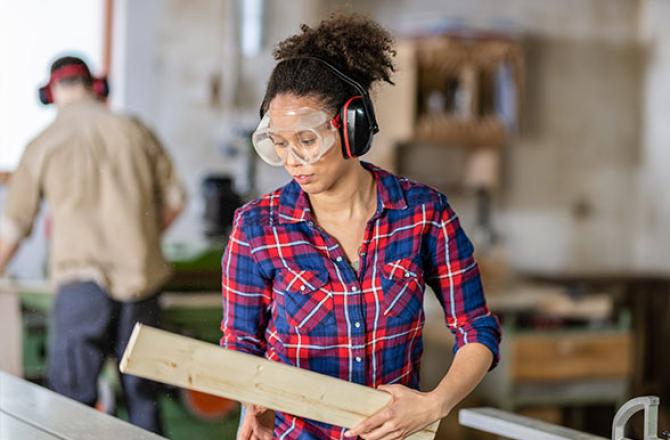 Woman wearing protective equipment in a woodshop.