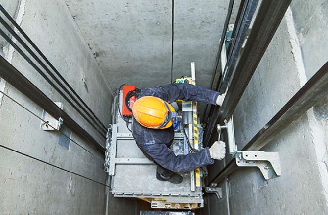 Elevating devices mechanic working on an elevator.