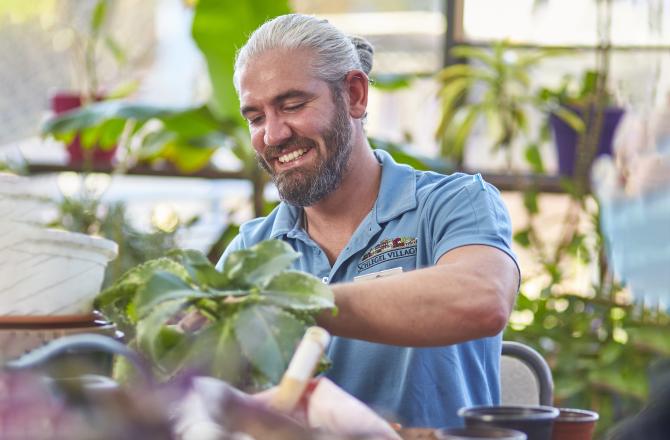 Mohawk College Alumni Tyson Creechan tending plants in the Schlegel Village greenhouse.