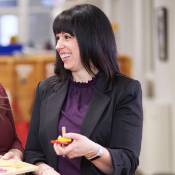 Woman smiles while holding children's toy.