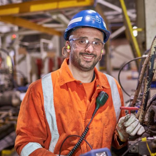 Man smiles as he operates mill machinery.