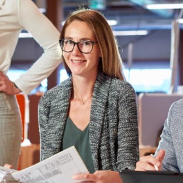 Woman smiles while reviewing blueprints with co-workers.