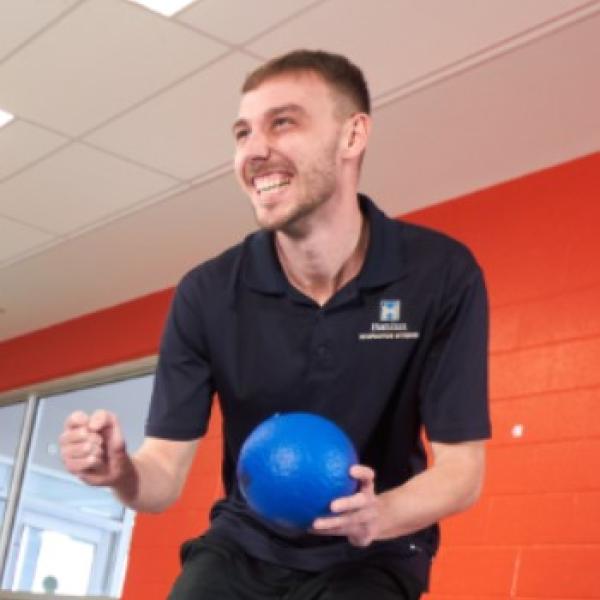 Man laughing with team member while holding a ball.