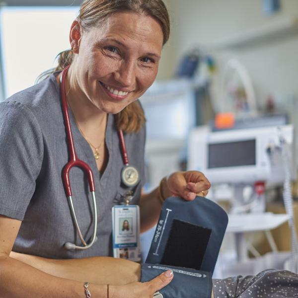 Woman smiles while using heart monitor machine on patient.