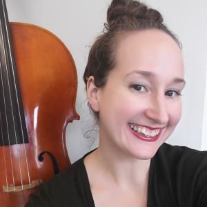 Jennifer Spleit's headshot. A picture of a woman with a double bass in the background.