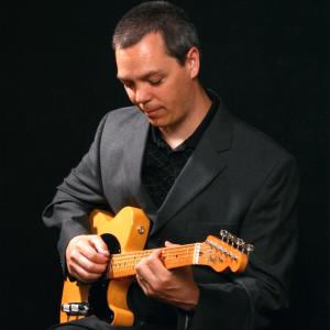 Mark Ucci playing guitar on stage.