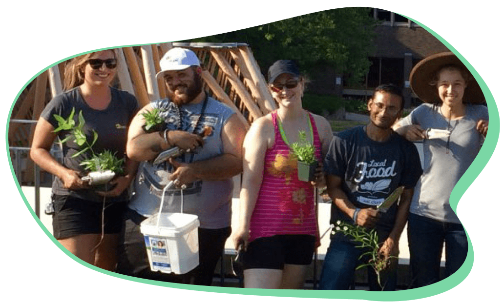 Volunteers posing for a picture while holding gardening equipment and plants